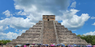 Teachers with protest signs and flags gather at the base of the Chichén Itzá pyramid