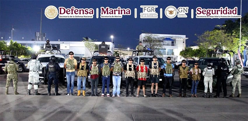 A photograph stamped with Mexican millitary logos shows 11 arrested radical successful subject gear, guarded by Mexican Army and National Guard troops