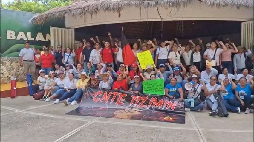 Protesters hold signs at Ek Balam
