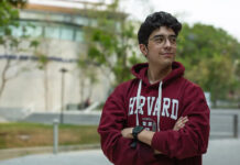 A young Mexican student wears a harvard sweatshirt