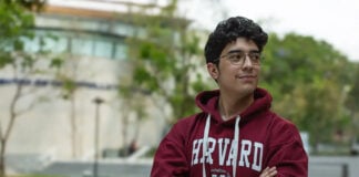 A young Mexican student wears a harvard sweatshirt