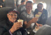 Travis and Tamanna Bembenek raise styrofoam cups to toast with Luis, an elderly Mexican man, on a plane