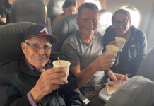 Travis and Tamanna Bembenek raise styrofoam cups to toast with Luis, an elderly Mexican man, on a plane