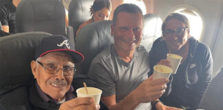 Travis and Tamanna Bembenek raise styrofoam cups to toast with Luis, an elderly Mexican man, on a plane