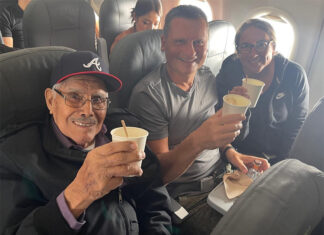 Travis and Tamanna Bembenek raise styrofoam cups to toast with Luis, an elderly Mexican man, on a plane