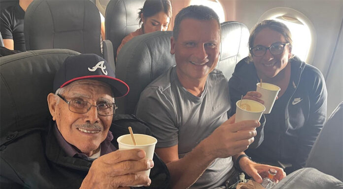 Travis and Tamanna Bembenek raise styrofoam cups to toast with Luis, an elderly Mexican man, on a plane