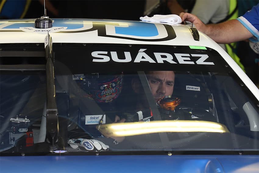 A man inside a NASCAR race car emblazoned with the name Suárez