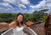 Nellie Huang, a woman with a tattoo of the world map on her arm takes a selfie in a Yucatán Peninsula forest.