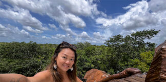 Nellie Huang, a woman with a tattoo of the world map on her arm takes a selfie in a Yucatán Peninsula forest.