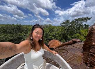 Nellie Huang, a woman with a tattoo of the world map on her arm takes a selfie in a Yucatán Peninsula forest.