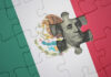 A United States dollar bill peeks out from behind a Mexican flag puzzle