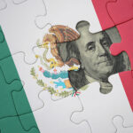 A United States dollar bill peeks out from behind a Mexican flag puzzle