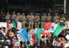 Protesters with Mexican flags and signs stand in front of a wall of California National Guard troops