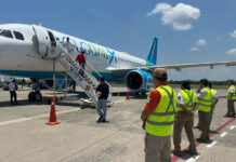 Men deboard a Global X airplane as Mexican airport workers and immigration agents stand by