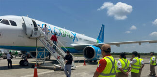 Men deboard a Global X airplane as Mexican airport workers and immigration agents stand by
