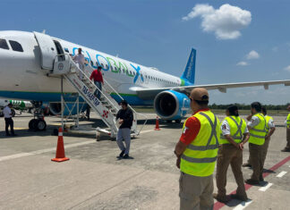Men deboard a Global X airplane as Mexican airport workers and immigration agents stand by