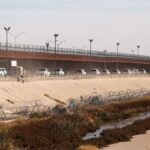 Border patrol vehicles drive along the US-Mexico border