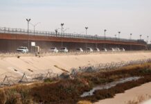 Border patrol vehicles drive along the US-Mexico border