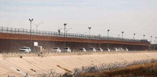 Border patrol vehicles drive along the US-Mexico border