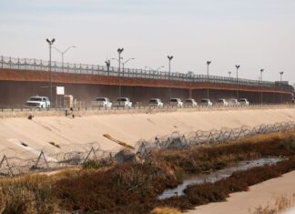 Border patrol vehicles drive along the US-Mexico border