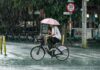 A man with an umbrella rides a bicycle in the rain in Mexico City
