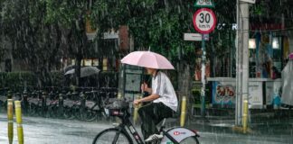 A man with an umbrella rides a bicycle in the rain in Mexico City