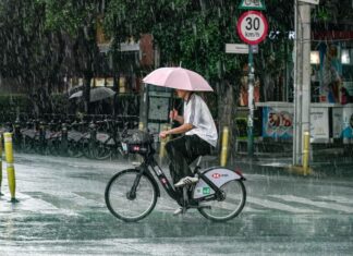 A man with an umbrella rides a bicycle in the rain in Mexico City