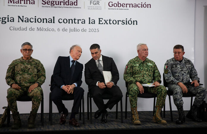Security chief Omar García Harfuch, Attorney General Gertz and other Mexian officials sit on a stage in front of a banner reading 