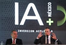 two men at podium with IA (AI in English) iage behind them.
