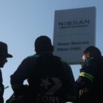 silhouetted figure in front of a Nissan sign