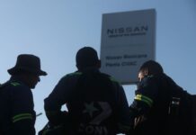 silhouetted figure in front of a Nissan sign
