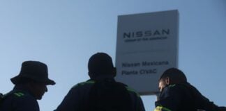 silhouetted figure in front of a Nissan sign