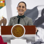 President Sheinbaum smiles from the podium of her morning press conference