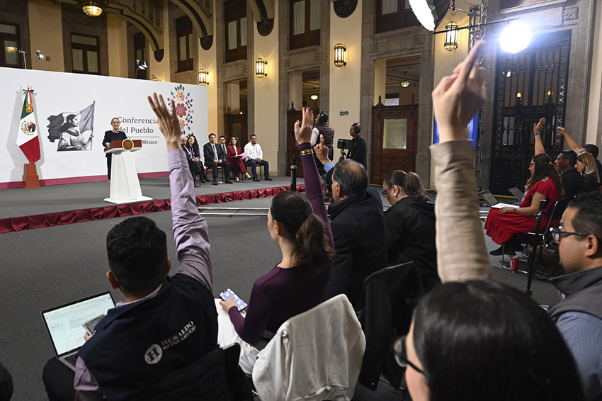 Reporters in the audience of President Sheinbaum's morning press conference raise their hands to ask questions