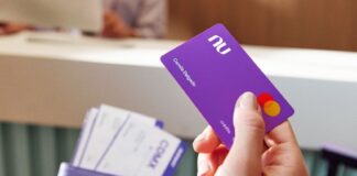 A close up shows a hand with a Nu credit card