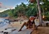 A woman in jaguar mask sitting on a beach