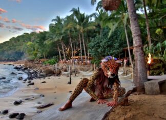 A woman in jaguar mask sitting on a beach