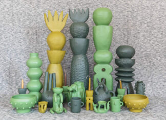 A collection of unique, handcrafted Mexican ceramic art pieces in shades of green and yellow, including tall stacked sculptures, vases, bowls, and whimsical figures, arranged on a textured grey surface.