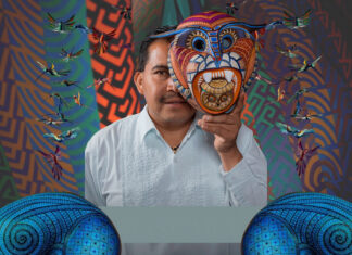 Artist Jacobo Ángeles holding a traditional Oaxacan folk art mask in front of his face.