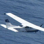 A small plane flies over the ocean