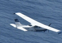 A small plane flies over the ocean
