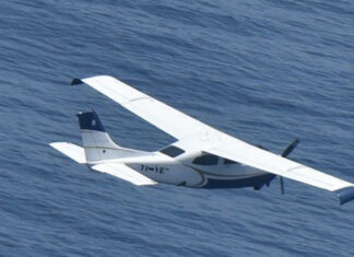 A small plane flies over the ocean