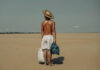 A photo of a shirtless man wearing white shorts stood on a beach