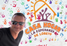 A man in sunglasses in front of a building entrance sign reading Casa Hogar La Esperanza de Loreto