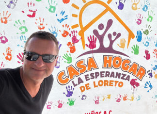 A man in sunglasses in front of a building entrance sign reading Casa Hogar La Esperanza de Loreto