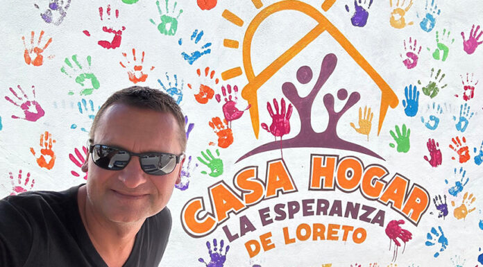 A man in sunglasses in front of a building entrance sign reading Casa Hogar La Esperanza de Loreto