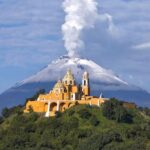 Nuestra Señora de los Remedios church in Cholula, Puebla, with Popocatépetl volcano smoking behind