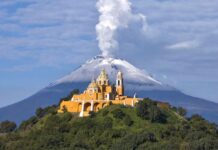 Nuestra Señora de los Remedios church in Cholula, Puebla, with Popocatépetl volcano smoking behind