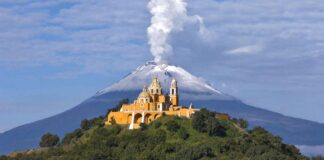 Nuestra Señora de los Remedios church in Cholula, Puebla, with Popocatépetl volcano smoking behind