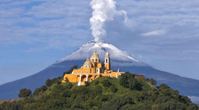 Nuestra Señora de los Remedios church in Cholula, Puebla, with Popocatépetl volcano smoking behind